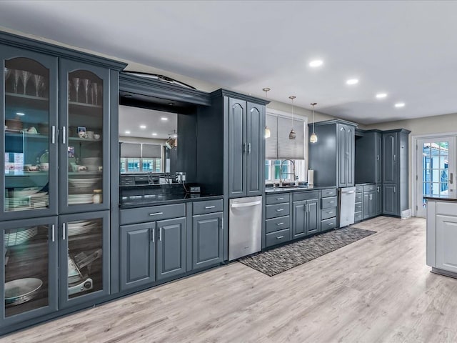 bar with light wood-type flooring, decorative light fixtures, stainless steel dishwasher, and sink