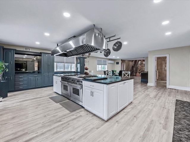 kitchen featuring island exhaust hood, white cabinetry, light hardwood / wood-style flooring, and range with two ovens