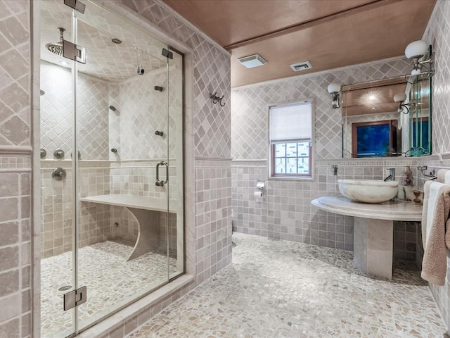 bathroom featuring sink, a shower with shower door, and tile walls