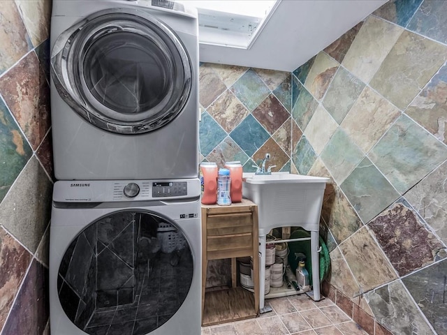 clothes washing area with stacked washer / dryer and tile walls