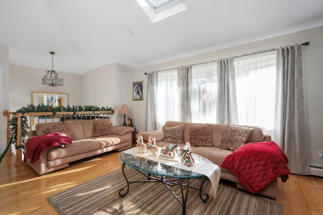 living room with a wealth of natural light, vaulted ceiling with skylight, and light hardwood / wood-style floors