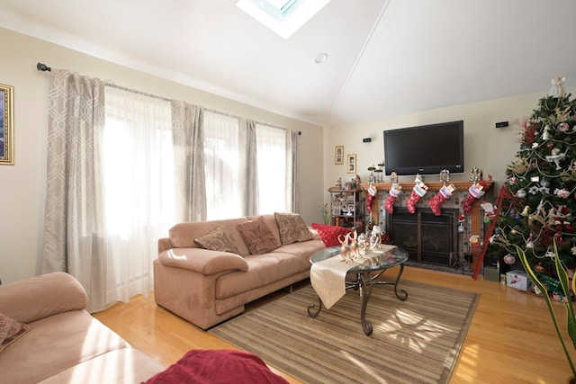 living room featuring hardwood / wood-style floors, vaulted ceiling, and a tiled fireplace