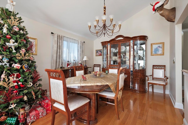 dining room with a chandelier, light hardwood / wood-style floors, and vaulted ceiling