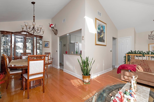 dining space with high vaulted ceiling, light hardwood / wood-style floors, and a notable chandelier