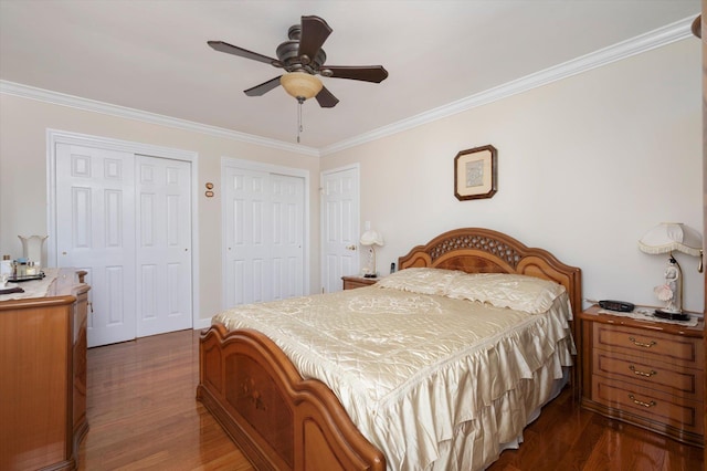 bedroom with ceiling fan, crown molding, dark wood-type flooring, and two closets