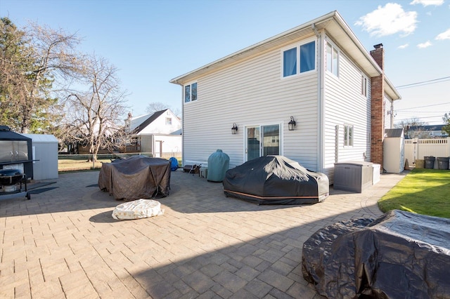 rear view of house featuring a storage unit and a patio area