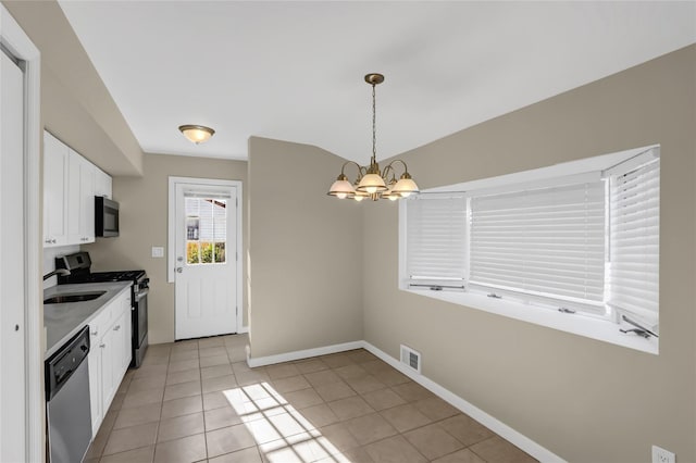 kitchen with an inviting chandelier, white cabinets, light tile patterned floors, decorative light fixtures, and stainless steel appliances