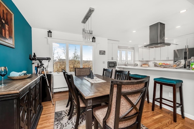 dining space featuring light hardwood / wood-style floors, sink, and a baseboard heating unit