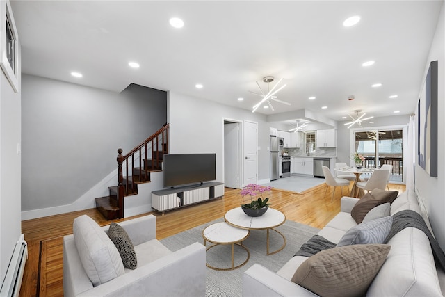 living room with light hardwood / wood-style flooring, a baseboard heating unit, and a notable chandelier