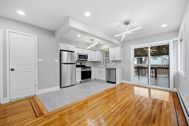 kitchen featuring white cabinets, stainless steel appliances, light wood-type flooring, and an inviting chandelier