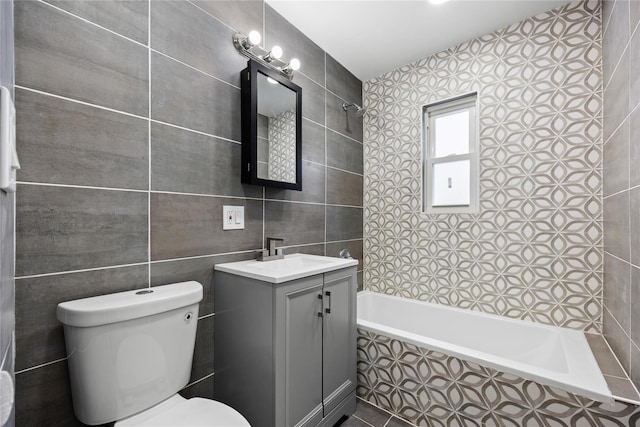 full bathroom featuring vanity, toilet, tile walls, and tiled shower / bath combo