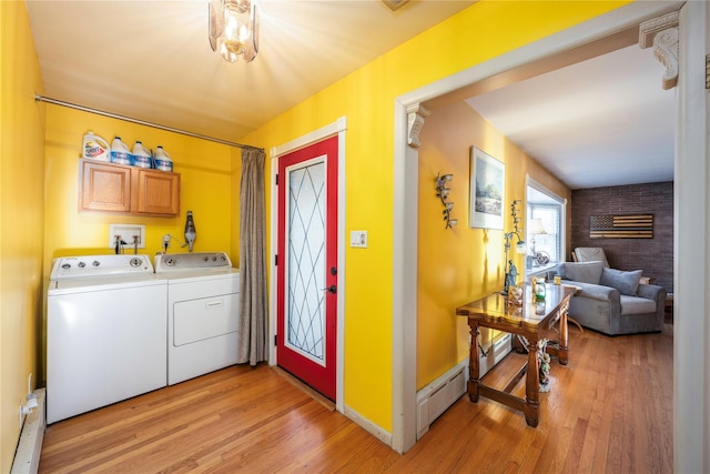 laundry area featuring washing machine and dryer, a baseboard radiator, cabinets, and light hardwood / wood-style floors