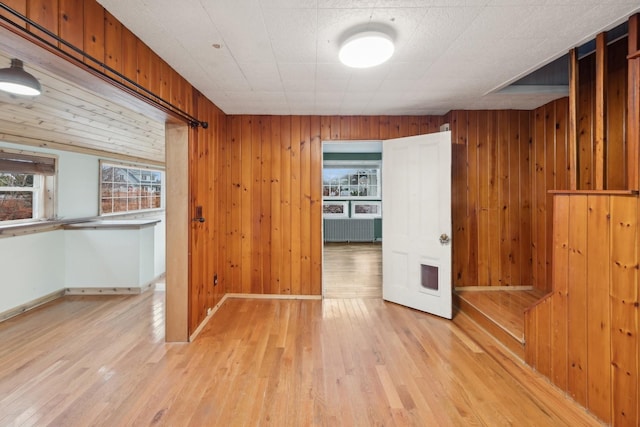 empty room with wooden walls and light hardwood / wood-style flooring