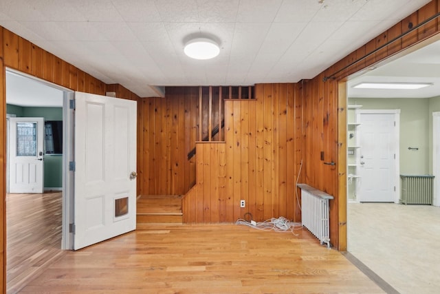 spare room with wood walls, wood-type flooring, and radiator