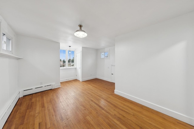 interior space with a baseboard heating unit and light hardwood / wood-style flooring