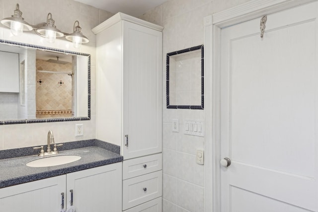 bathroom with a tile shower, tasteful backsplash, vanity, and tile walls