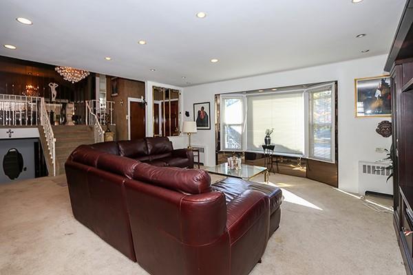 carpeted living room with a chandelier and radiator heating unit