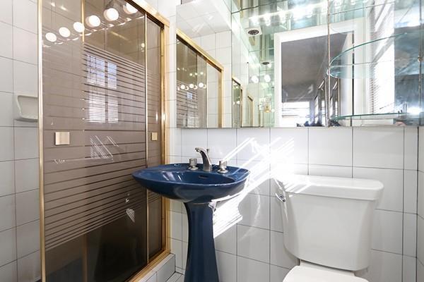 bathroom with sink, toilet, a shower with shower door, and tile walls