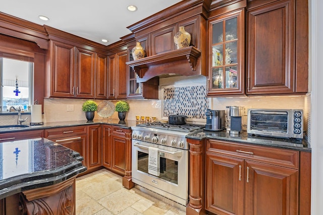 kitchen featuring high end range, backsplash, dark stone counters, and sink