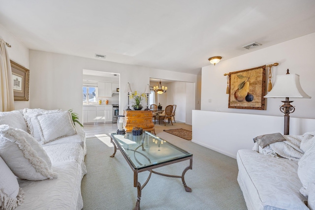 carpeted living room featuring an inviting chandelier