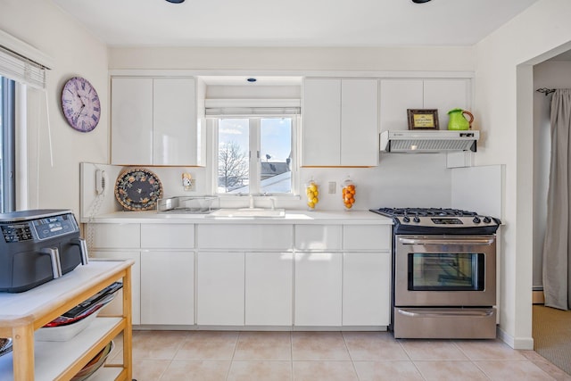 kitchen with sink, light tile patterned floors, stainless steel gas range, extractor fan, and white cabinets