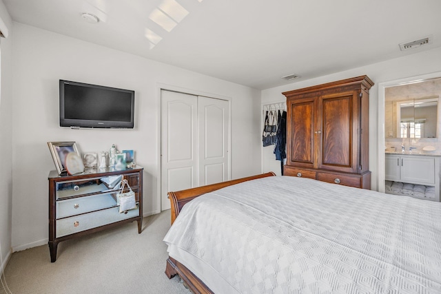 carpeted bedroom with ensuite bathroom and a closet