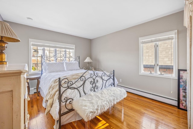 bedroom with hardwood / wood-style floors and a baseboard radiator