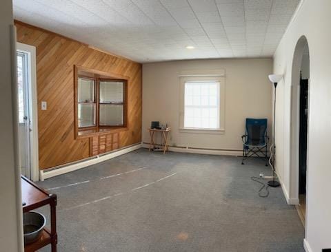 unfurnished room featuring baseboard heating and wood walls