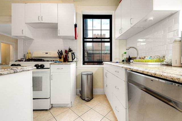 kitchen featuring light tile patterned floors, white cabinetry, white gas range, and light stone counters