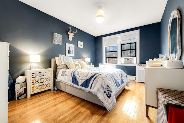 bedroom with ceiling fan, cooling unit, and light hardwood / wood-style flooring