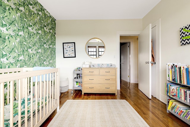 bedroom with a crib and dark hardwood / wood-style flooring