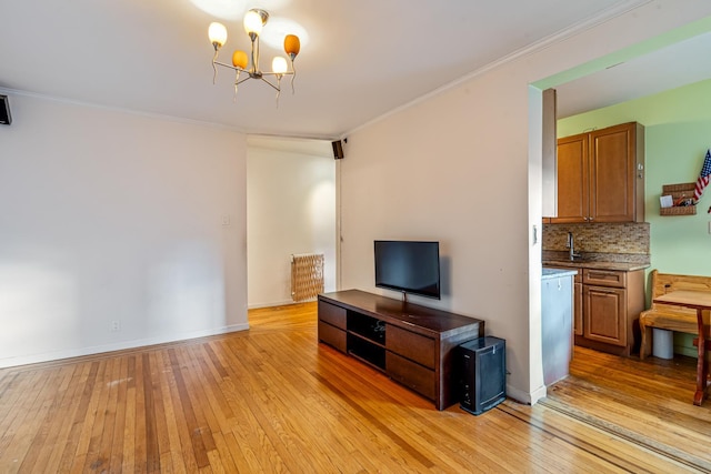 living room with light hardwood / wood-style floors, sink, crown molding, and an inviting chandelier