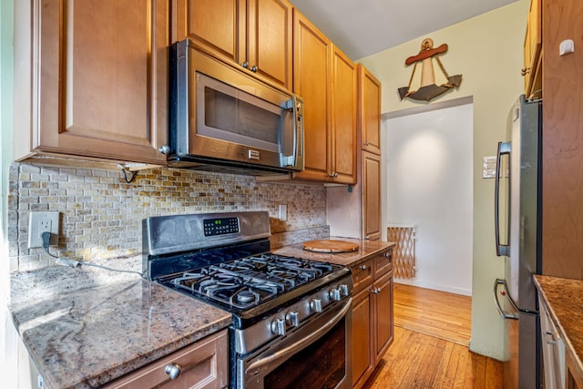 kitchen featuring tasteful backsplash, light hardwood / wood-style floors, stone countertops, and appliances with stainless steel finishes