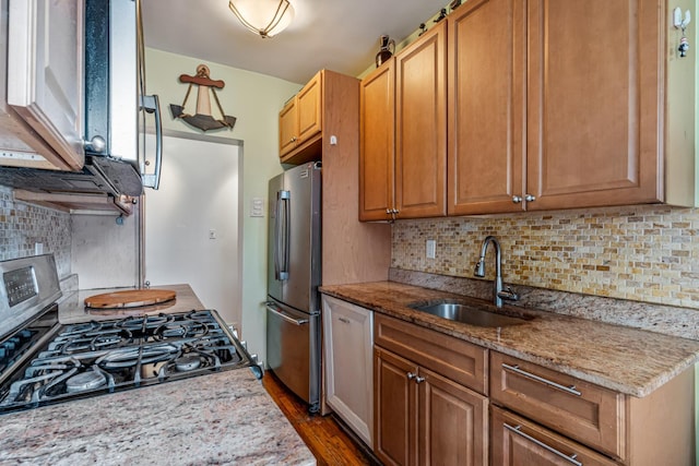 kitchen featuring light stone countertops, appliances with stainless steel finishes, tasteful backsplash, dark wood-type flooring, and sink