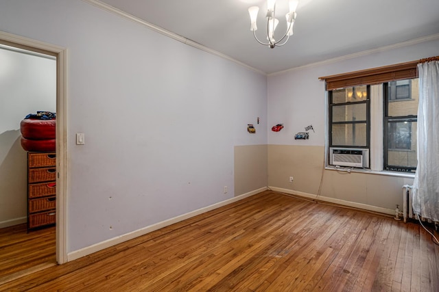 spare room with crown molding, cooling unit, wood-type flooring, and a notable chandelier