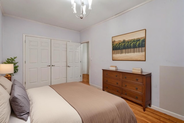 bedroom featuring light wood-type flooring, an inviting chandelier, a closet, and ornamental molding