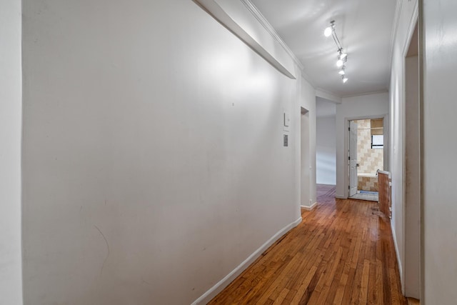 hall with rail lighting, wood-type flooring, and ornamental molding