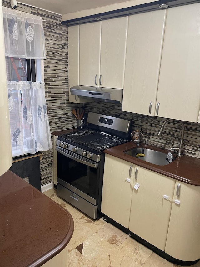 kitchen with stainless steel gas stove, sink, and tasteful backsplash