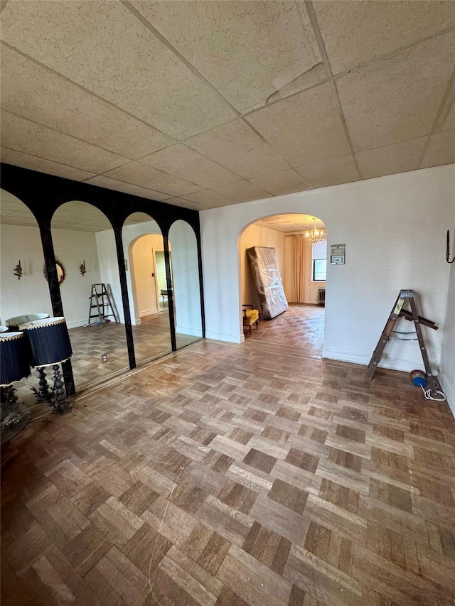 basement featuring a paneled ceiling and a chandelier