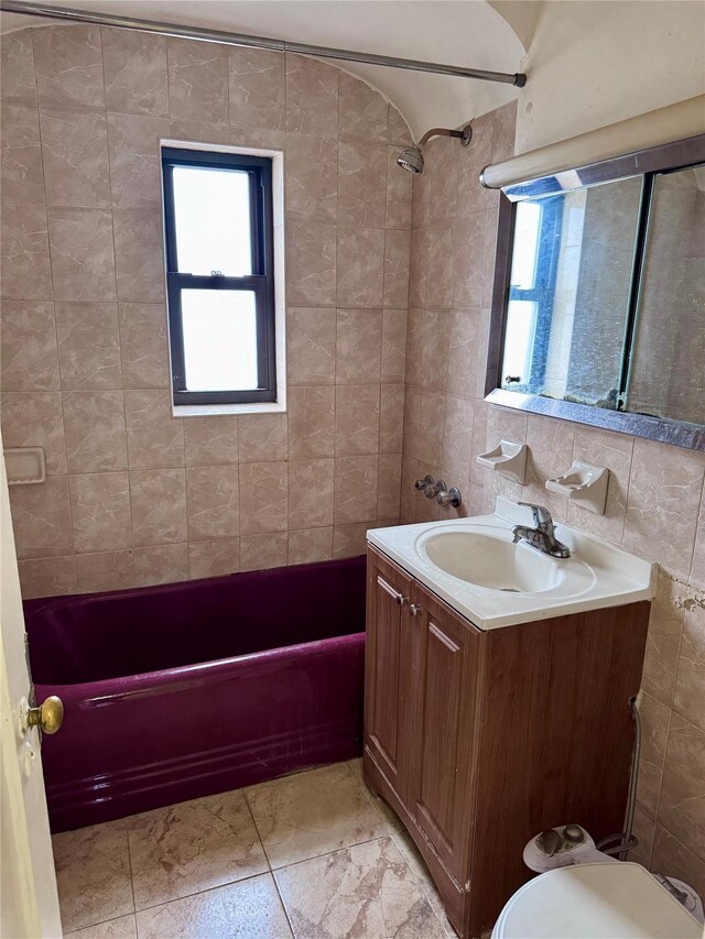 full bathroom with decorative backsplash, vanity, tiled shower / bath combo, and tile walls