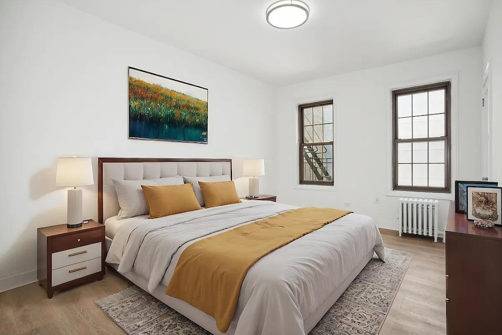 bedroom featuring radiator heating unit and light wood-type flooring