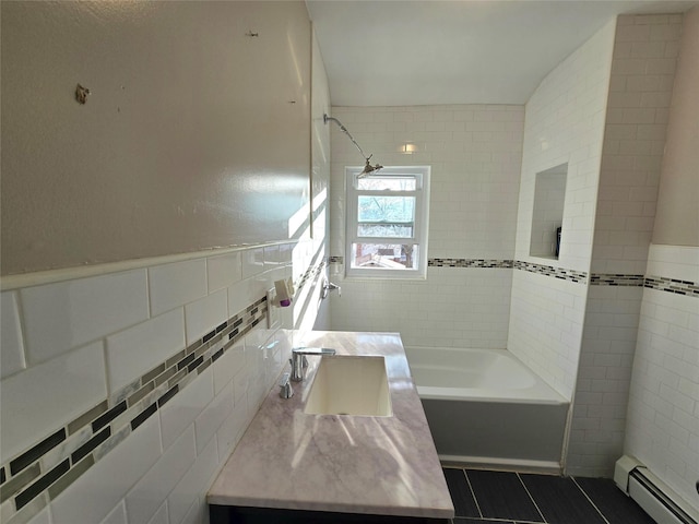 bathroom with tile patterned flooring, vanity, tile walls, tiled shower / bath, and a baseboard radiator