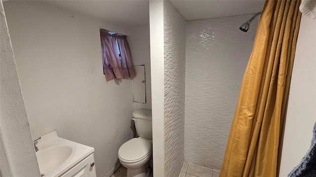 bathroom featuring toilet, tile patterned flooring, tiled shower, and vanity