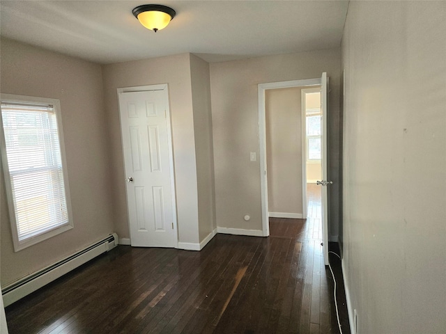 unfurnished bedroom with a baseboard heating unit, a closet, and dark hardwood / wood-style flooring