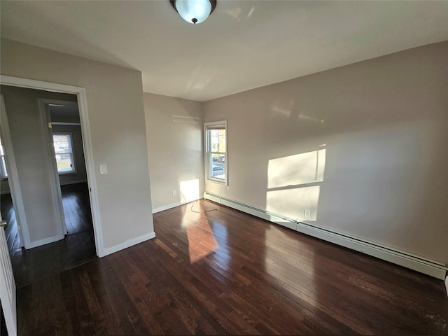 unfurnished room with baseboard heating, dark wood-type flooring, and a healthy amount of sunlight