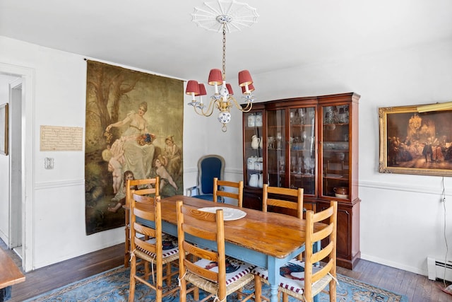 dining area featuring a notable chandelier, dark hardwood / wood-style floors, and a baseboard heating unit