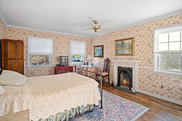 bedroom featuring ceiling fan, wood-type flooring, crown molding, and multiple windows