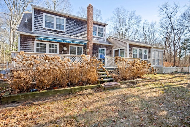 back of property with a lawn, a sunroom, and a deck