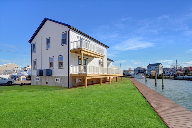 rear view of house featuring a lawn, a balcony, and a water view