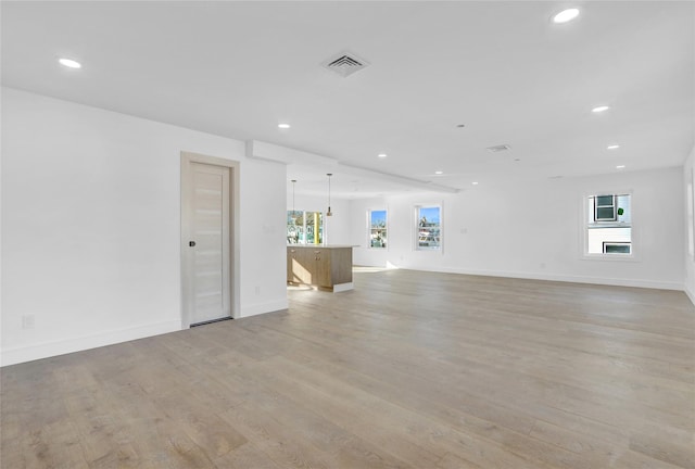 unfurnished living room featuring a wealth of natural light and light hardwood / wood-style floors